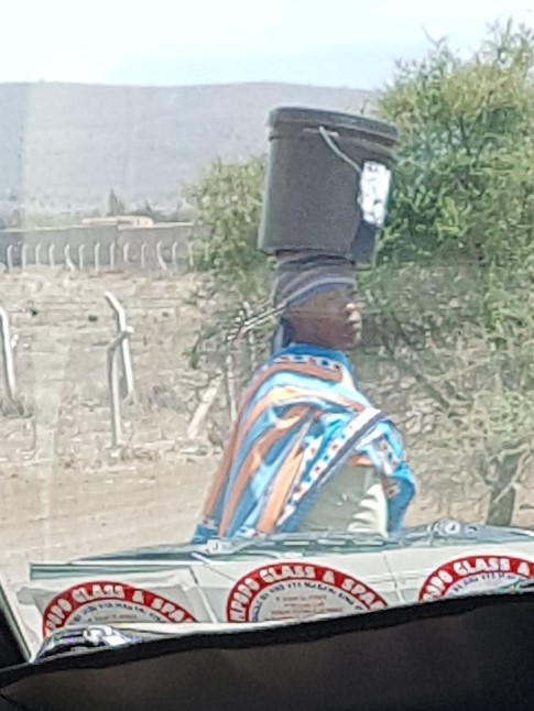 Maasai woman carrying bucket on head