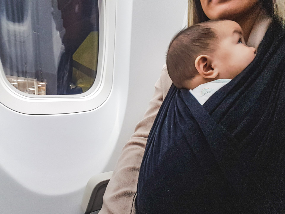 Baby sleeping on airplane in wrap carrier